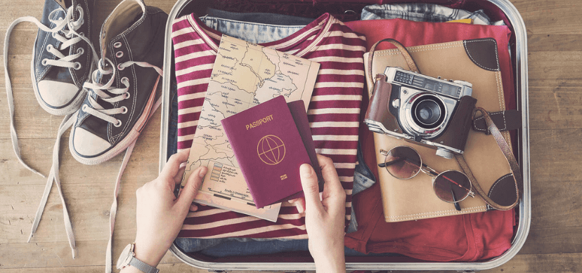 Maleta de viaje con una cámara de fotos, un mapa, un pasaporte y ropa Traveltech