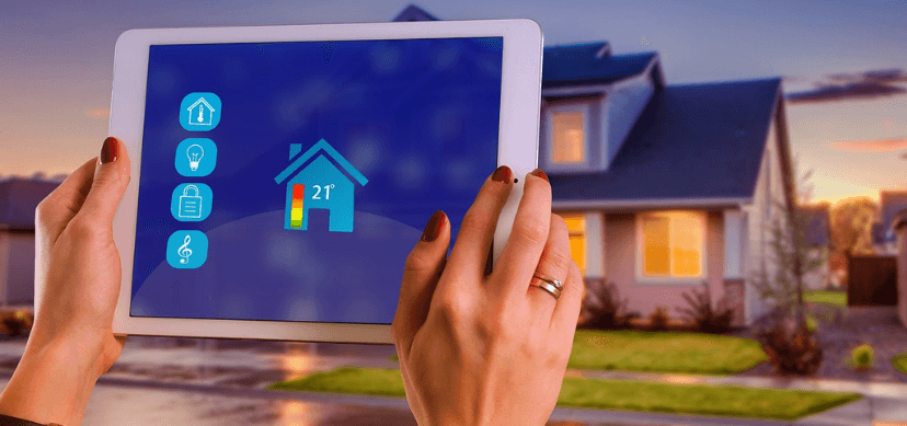 Tablet enfrente de una casa como dispositivo de IoT instalado en el hogar
